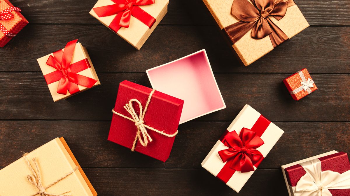 A festive flat lay of various Christmas presents adorned with colorful ribbons on a wooden background.
