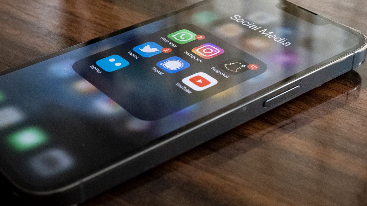 Close-up of smartphone on table showing various social media app icons including WhatsApp and Instagram.