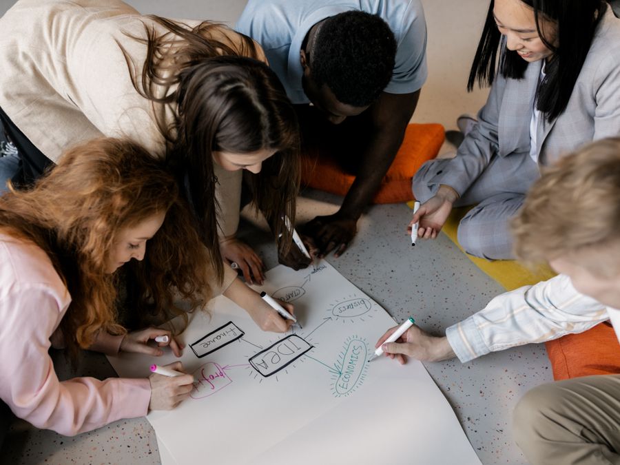 A diverse team of young adults collaborating on a startup project with brainstorming sketches.