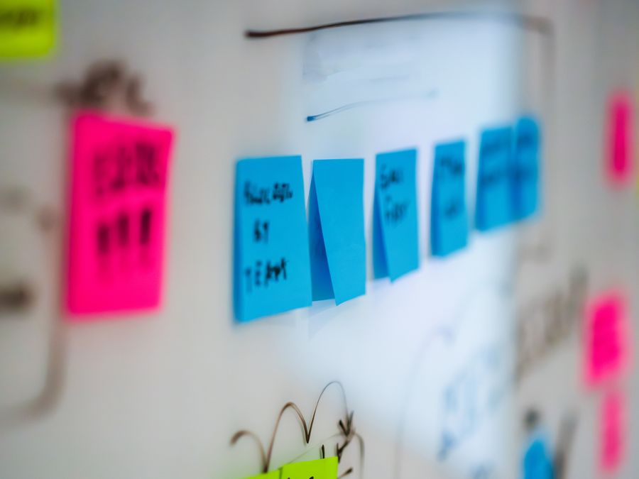 Sticky notes on a whiteboard during a creative brainstorming session in an office.