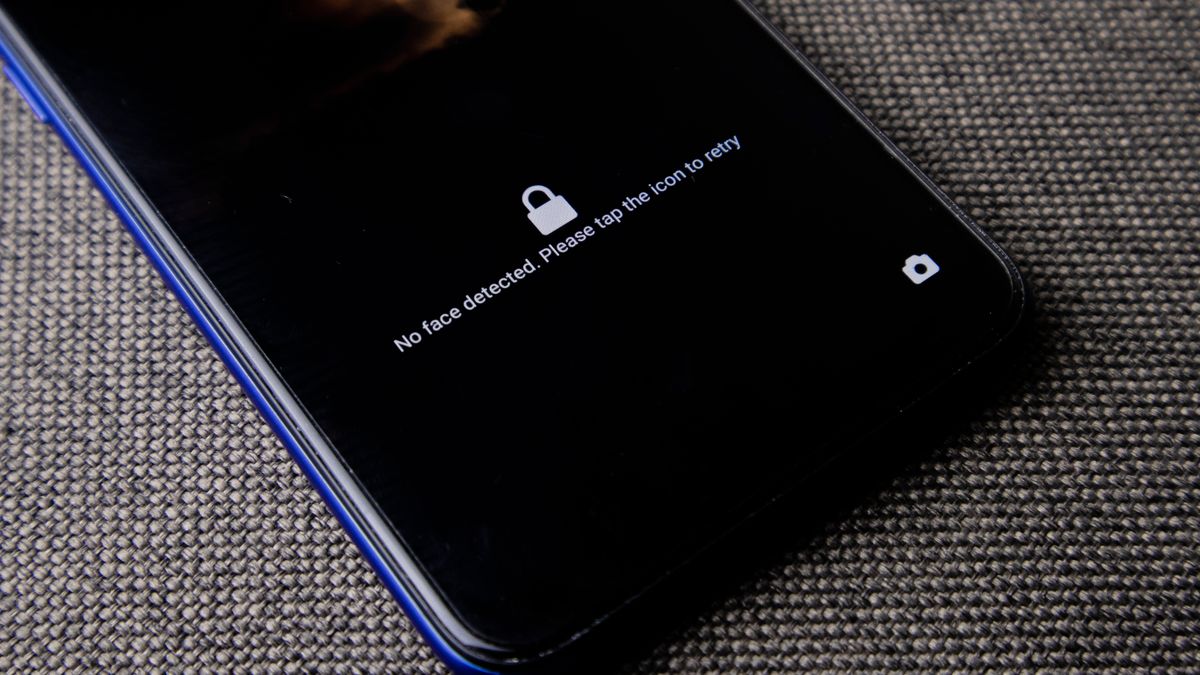 Mobile phone with no face detected message on lock screen on a textured fabric surface.