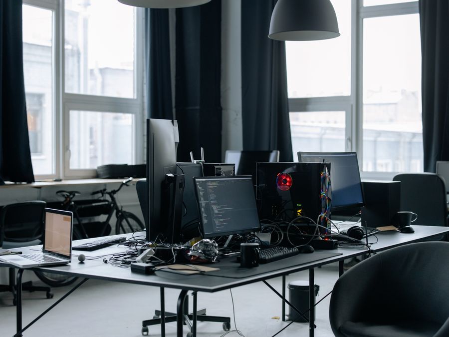 Contemporary workspace featuring computers, coding screens, and office essentials in a tech environment.