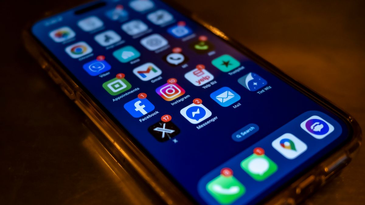 Smartphone screen displaying social media app notifications in a dimly lit setting.