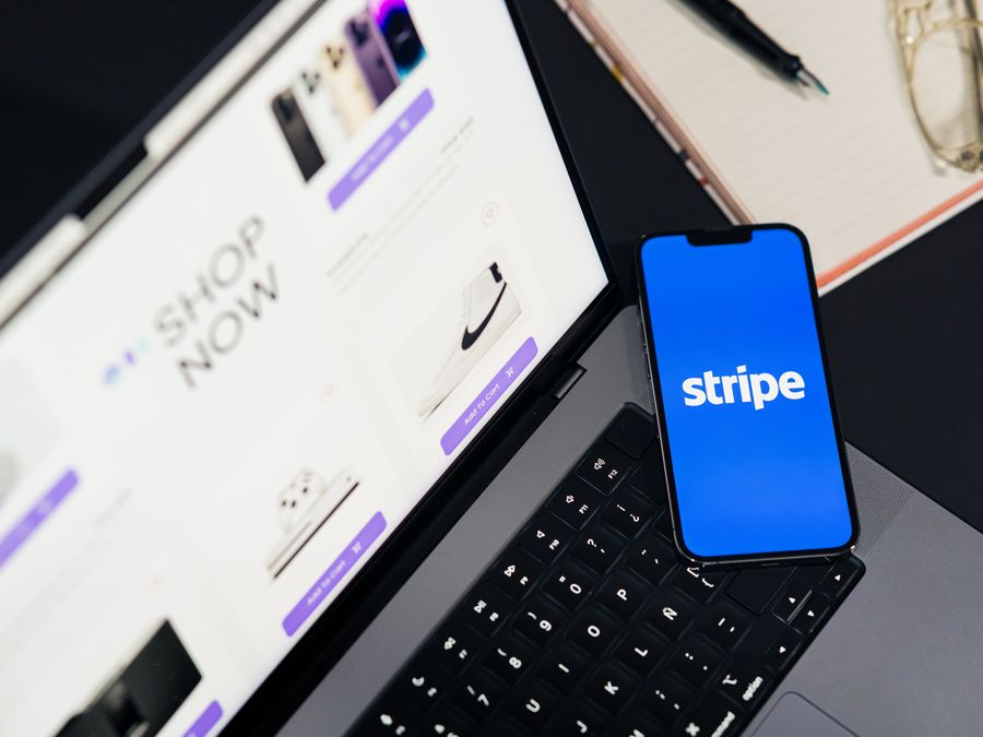 Mobile phone displaying Stripe app on a laptop with an eCommerce site open, symbolizing online shopping.