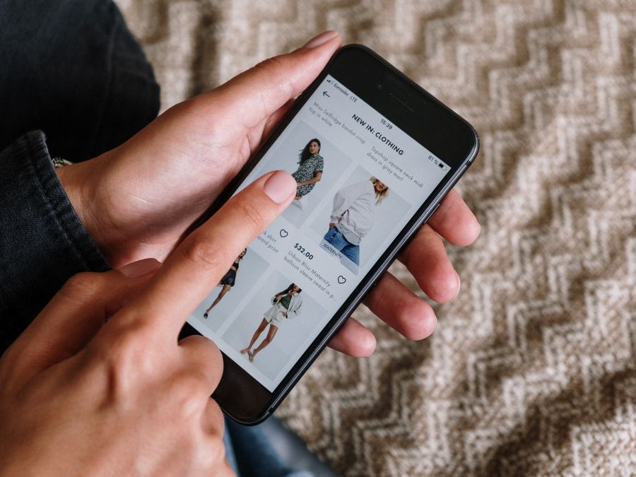 Person browsing clothing items on a smartphone, showcasing modern online shopping experience.