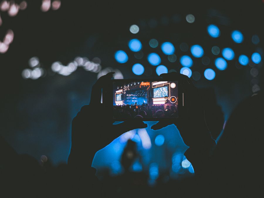 A vibrant concert scene captured through a smartphone, showcasing lively bokeh lights.