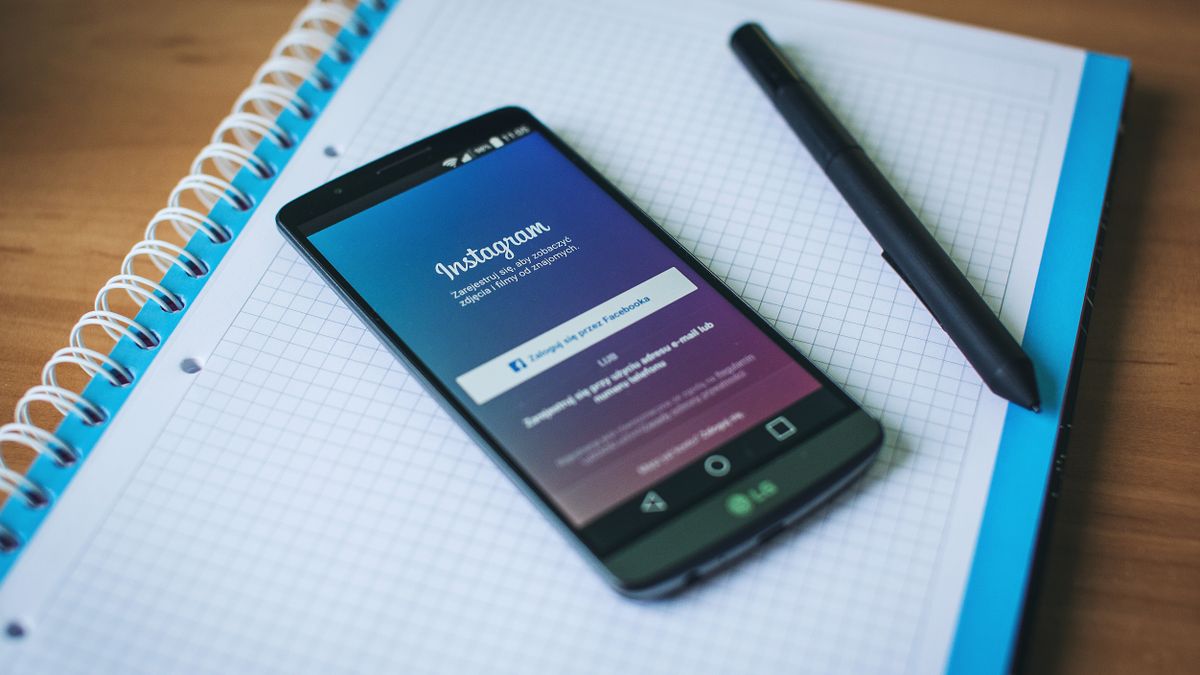 A smartphone displaying Instagram on a notepad with a pen, symbolizing social media and productivity.