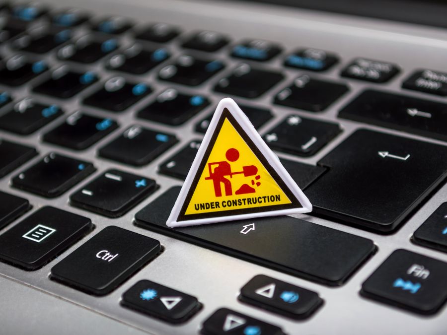 A miniature under construction sign placed on a laptop keyboard symbolizing digital development.