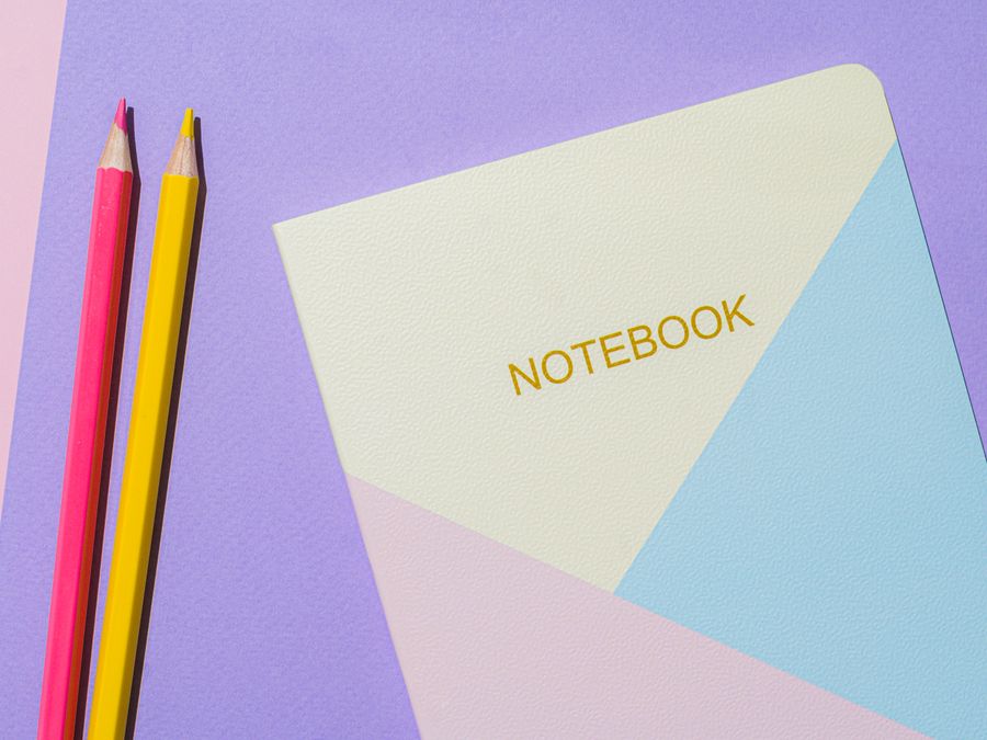 A vibrant flat lay composition featuring a notebook and colored pencils on a pastel background.