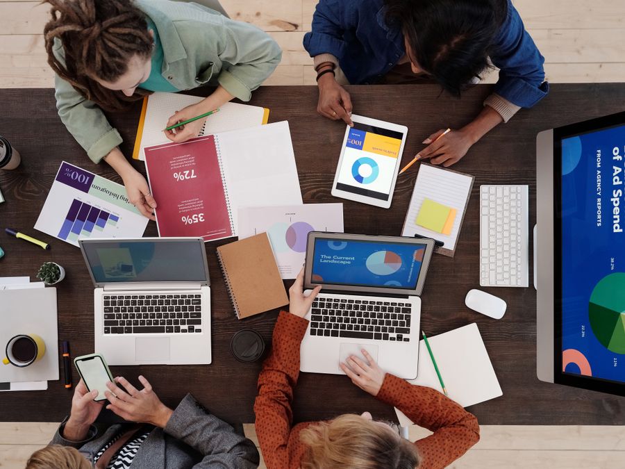 A diverse team collaborating on digital marketing strategies at a desk, using laptops and tablets.