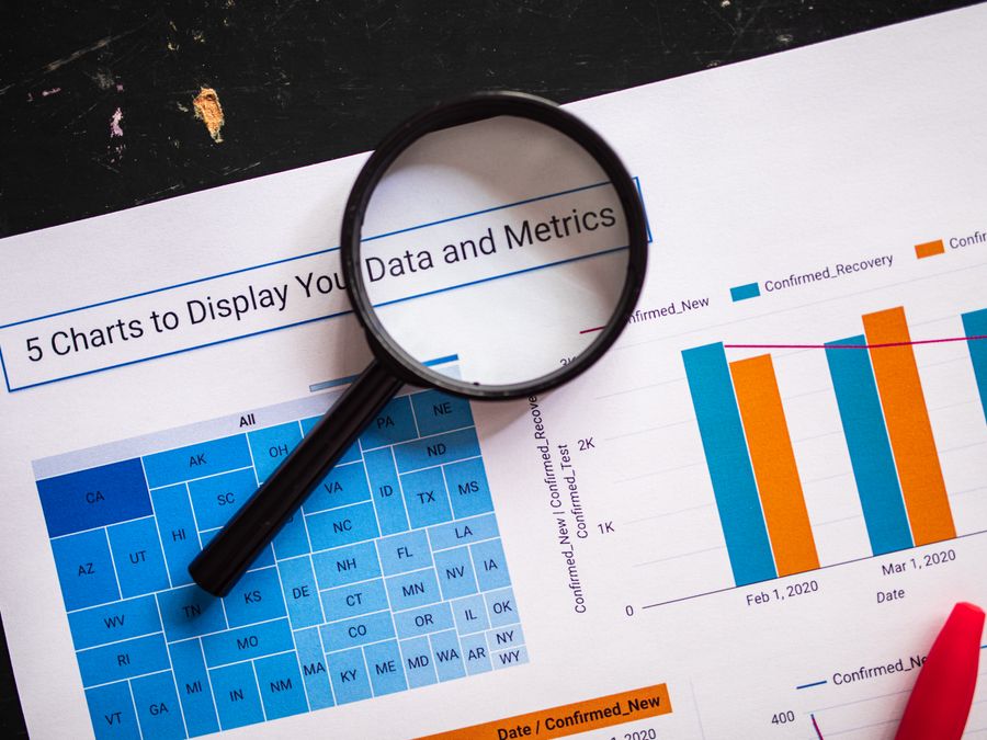 Close-up of business charts with magnifying glass highlighting data insights.