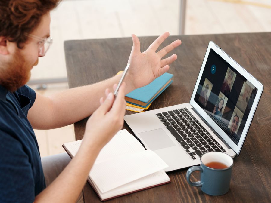 Man engaged in a virtual meeting at home with laptop and tea, chatting and studying online.
