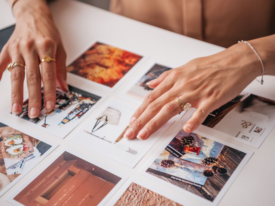 Hands arranging photo prints on a table, showcasing creativity and organization in content creation.
