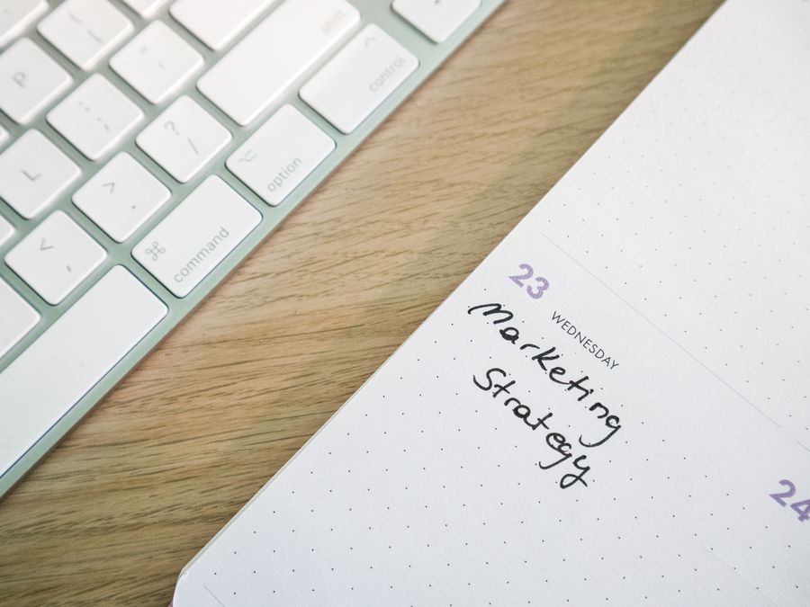 Close-up of a desk with a keyboard and a calendar open to a marketing strategy note.