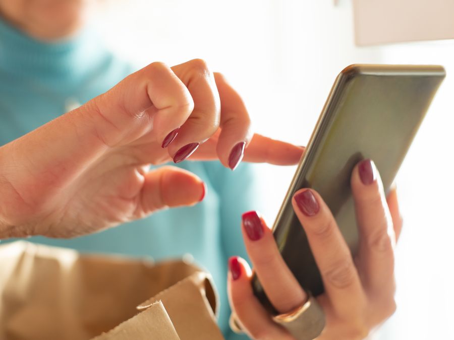 Hands interacting with a smartphone screen indoors, showcasing modern technology and connectivity.