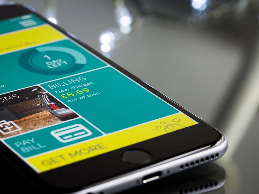 Close-up of a smartphone displaying a billing app interface on a reflective surface.