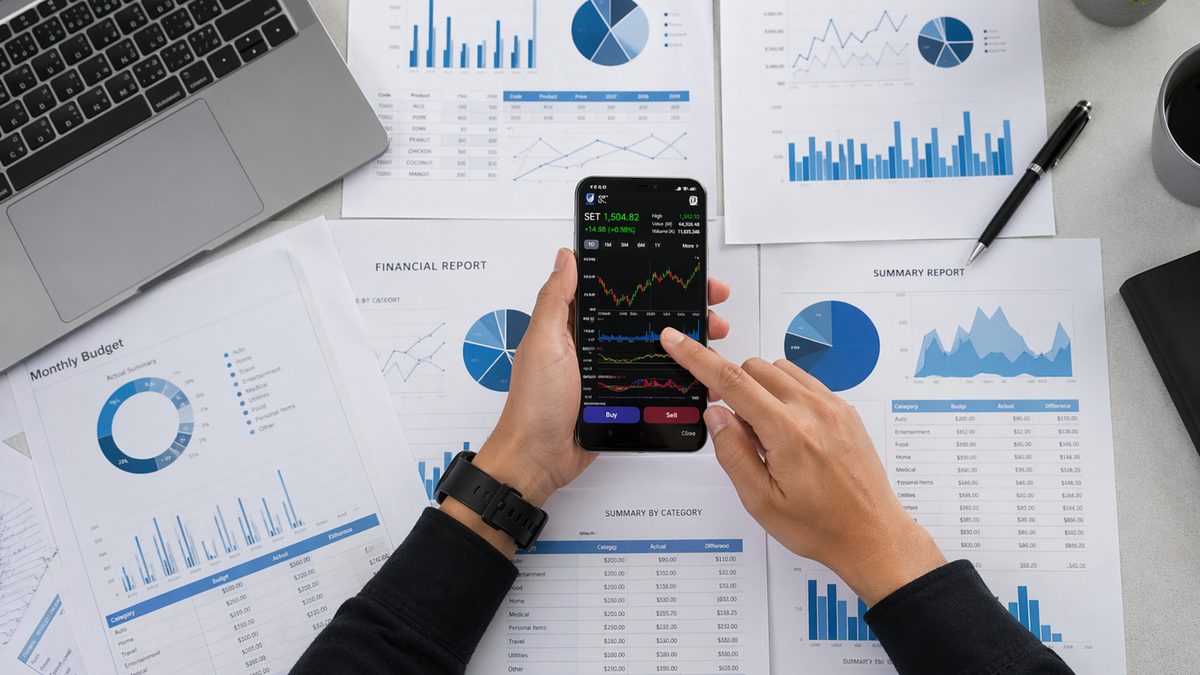 Business person reviews financial data and graphs on a mobile device surrounded by reports.