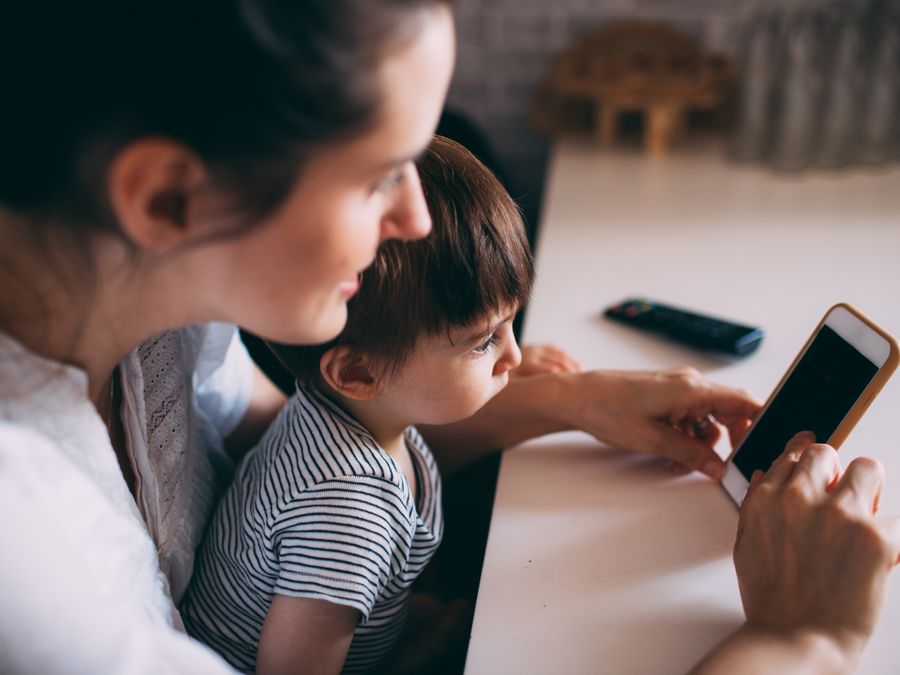 A mother and child bonding while using a smartphone at home.