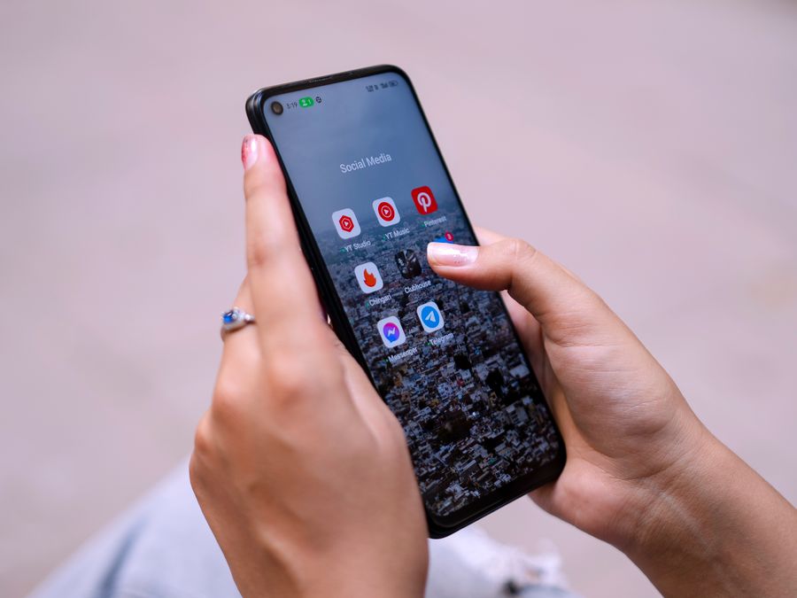 Close-up of hands holding a smartphone displaying social media apps, emphasizing digital connectivity.
