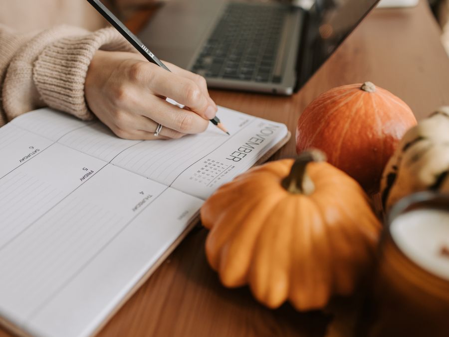 A cozy workspace with a planner, pumpkins, and a laptop, capturing the essence of autumn planning.