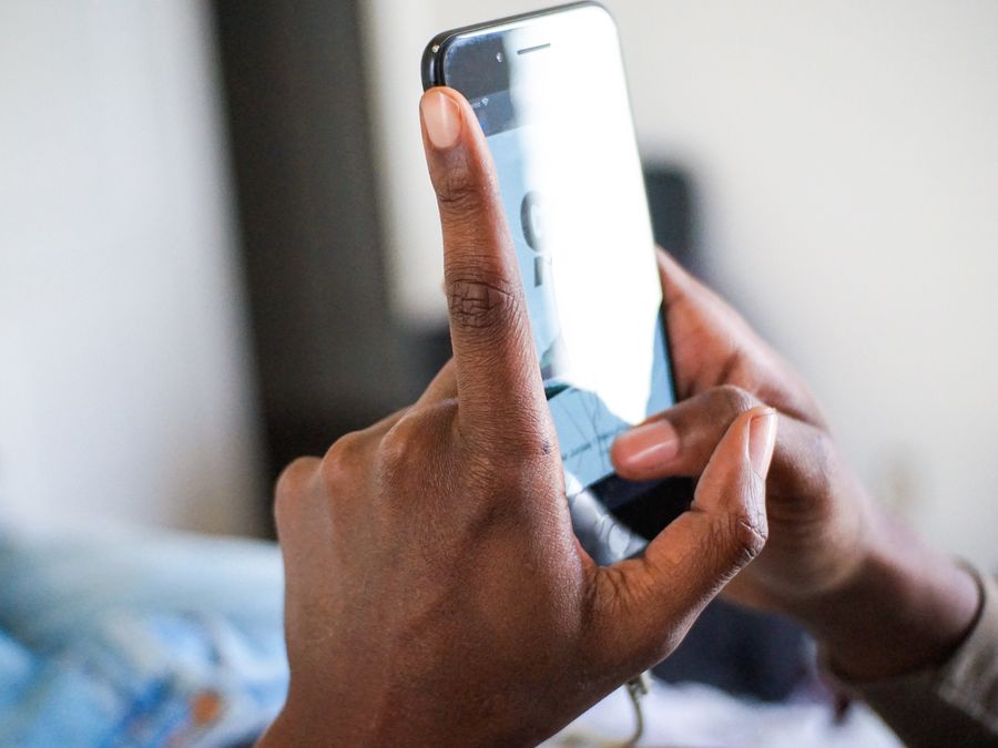 African American hand holding and using a smartphone, focus on texting gesture.