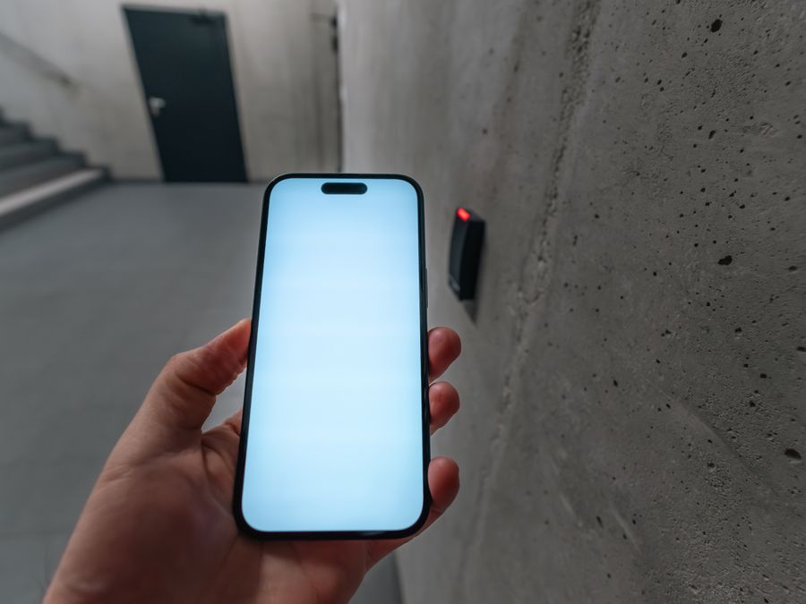A smartphone unlocking a secure door using NFC technology in a modern building stairwell.