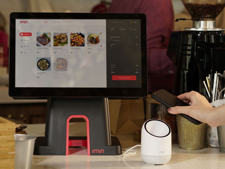 A modern point of sale system with contactless payment capability in a cafe setting.