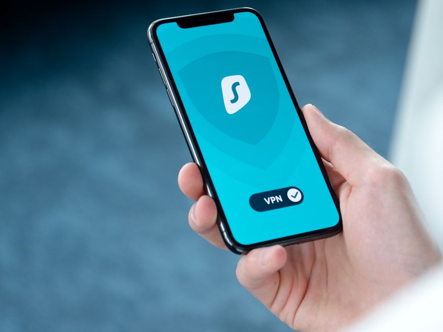 A hand holding a smartphone displaying a VPN app screen for secure online browsing.