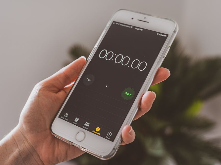 Smartphone held in hand displaying a stopwatch timer app.