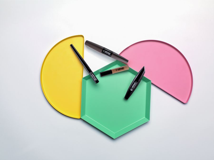 Creative composition of beauty products on colorful geometric shapes with clean white background.