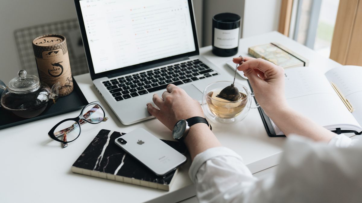 A cozy home office scene with a laptop, tea, and workspace essentials.