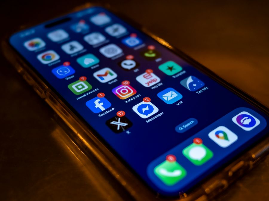 Smartphone screen displaying social media app notifications in a dimly lit setting.