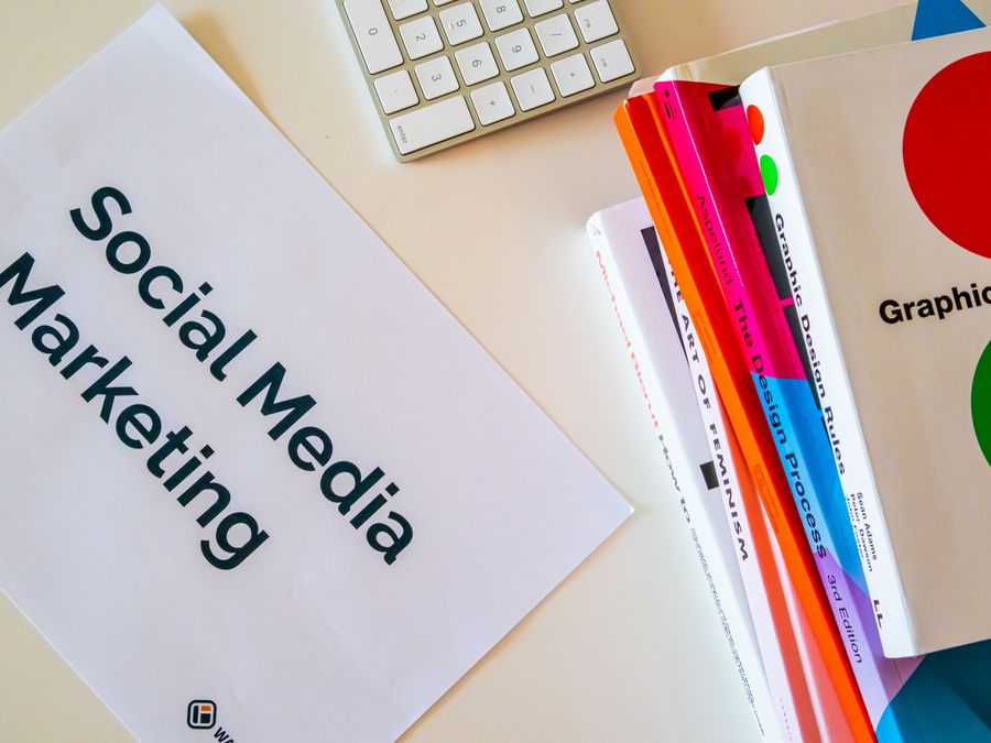A top view of social media marketing text alongside graphic design books and a keyboard.