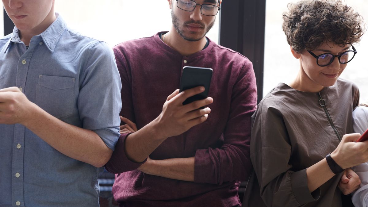 A diverse group of people actively using smartphones indoors. Modern technology and social interaction.