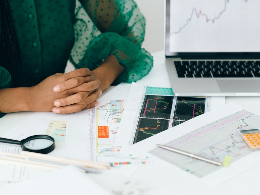 A person analyzes financial charts and graphs at a desk, indicating business trading activity.