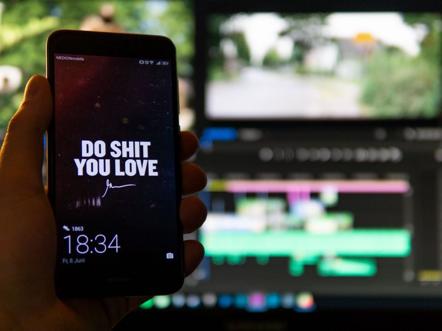 Close-up of a smartphone displaying an inspirational message against a video editing background.
