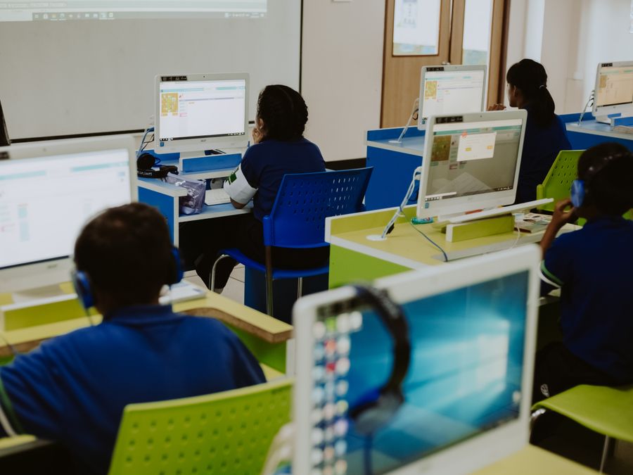 Children engaged in learning at computers in a modern classroom setting, promoting digital literacy.