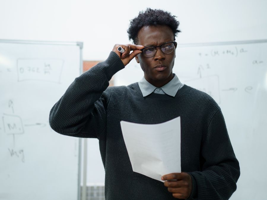 Focused businessman reading documents in an office setting with whiteboards.