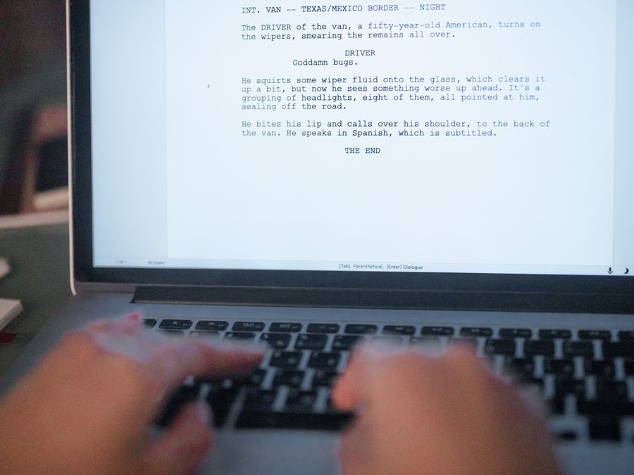 A close-up shot of hands typing a film script on a laptop, focusing on creativity and screenplay writing.