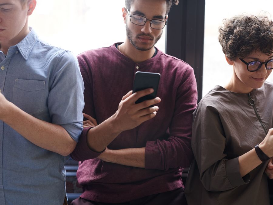A diverse group of people actively using smartphones indoors. Modern technology and social interaction.