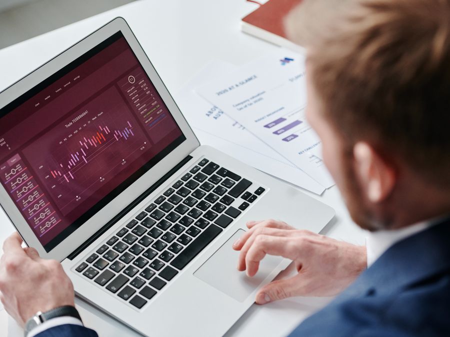 Businessman reviewing data analytics dashboard on laptop in bright office.