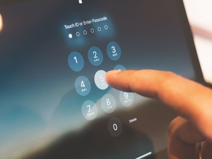 Close-up of a finger entering a passcode on a smartphone security screen.