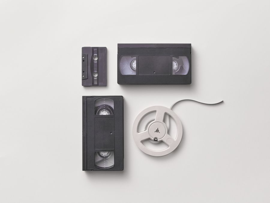 Collection of vintage audio and video tapes including VHS and cassette on a white background.