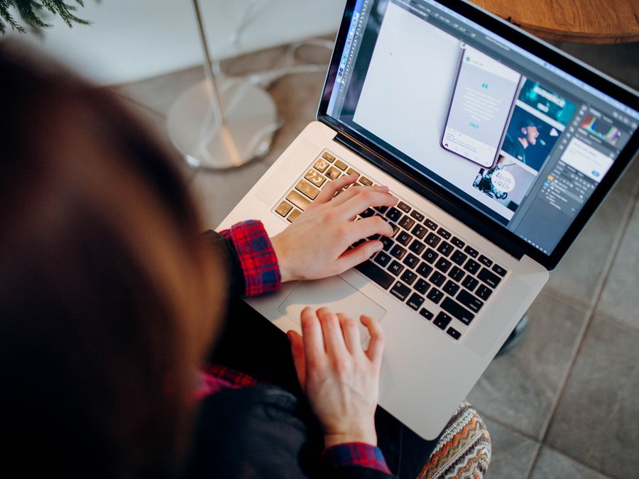 Close-up of a person working on a laptop with graphic design software.
