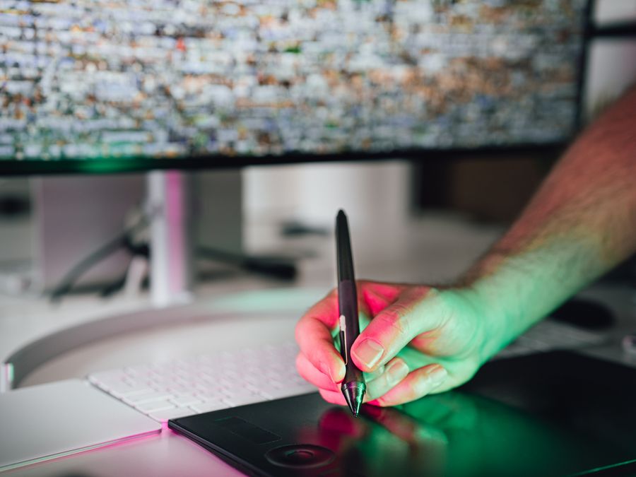 A digital artist using a graphics tablet and stylus in a modern workspace. High-tech creative process.