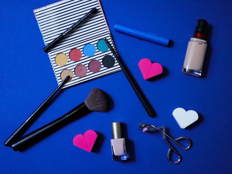 Colorful makeup products arranged stylishly on a blue backdrop for beauty inspiration.
