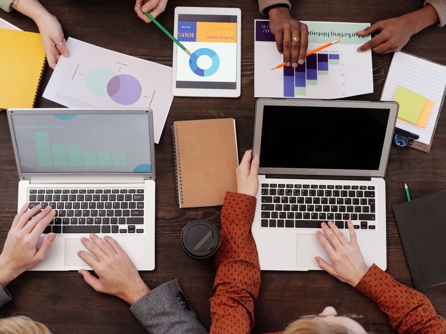 Overhead view of a team discussing digital marketing strategies with laptops and charts.