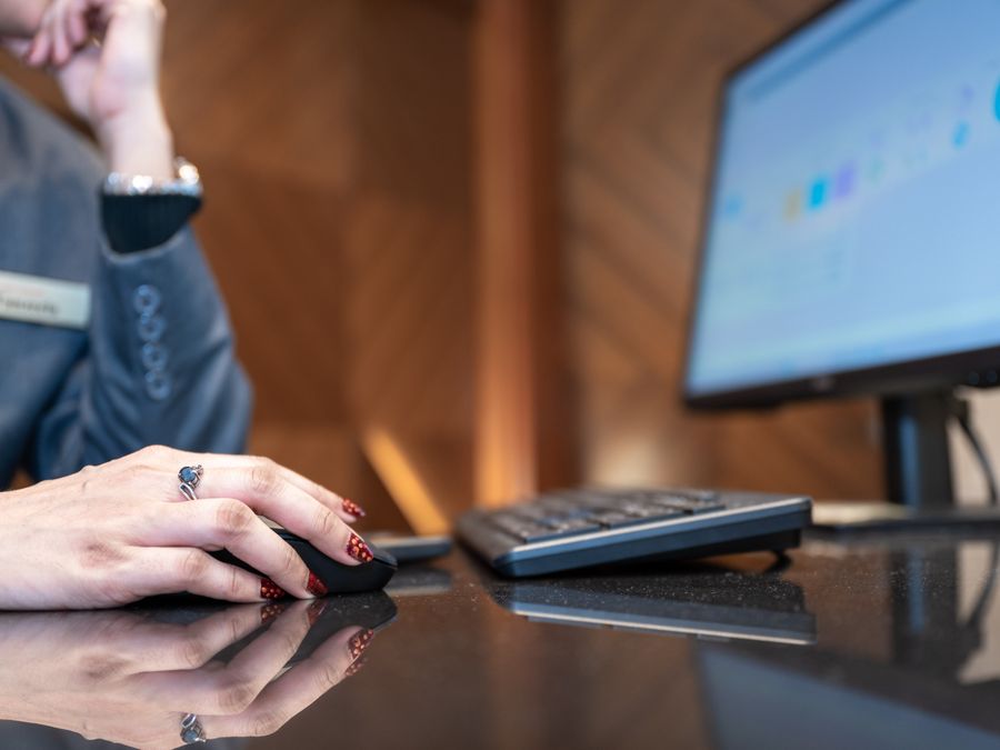 Close-up of a business professional using a computer mouse and keyboard in a modern office environment.