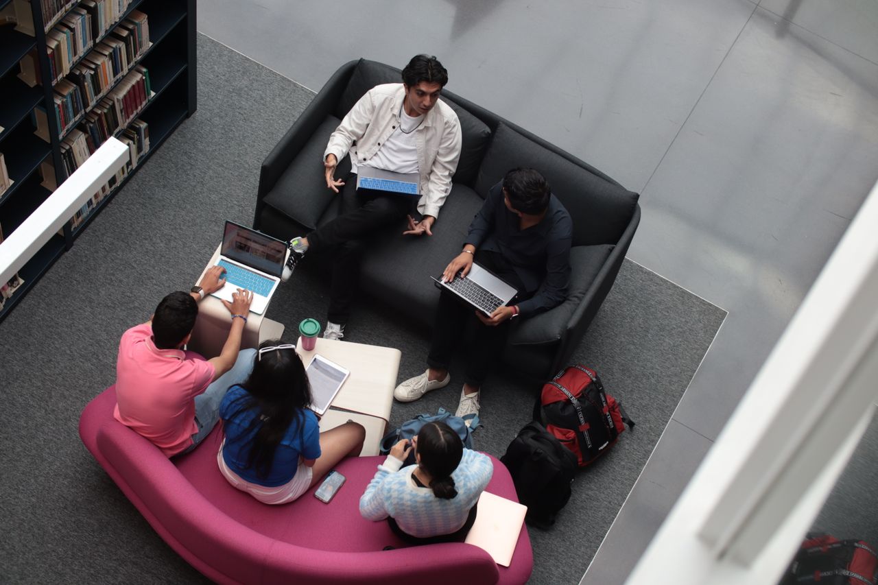 Students studying together with laptops in a modern library